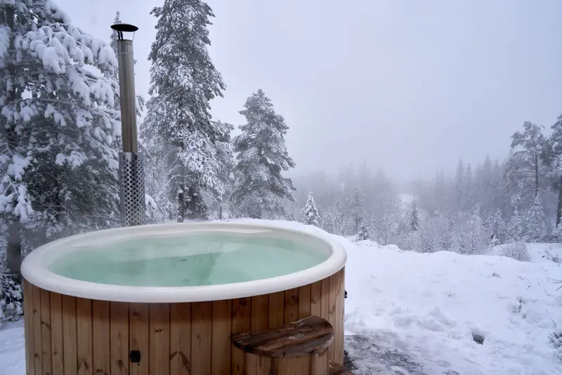 Relaxing hot tub amidst snow-covered trees in a serene Norwegian winter landscape
