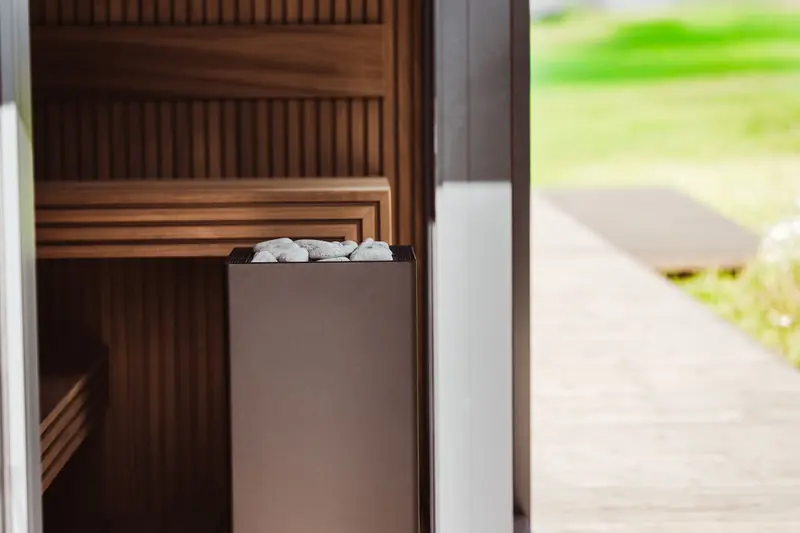 Contemporary outdoor sauna featuring wood panels and an electric heater with stones
