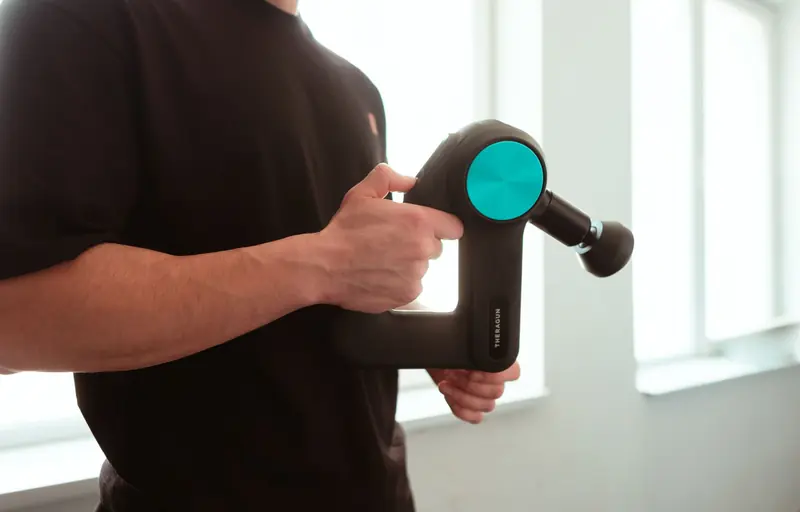 Close-up of a man using a massage device indoors with soft lighting